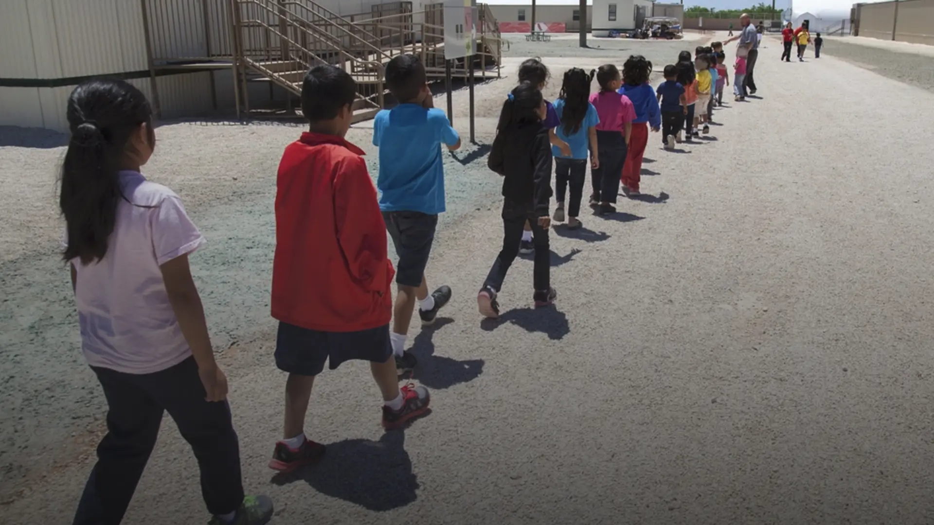 Niños caminando en fila dentro de un centro de detención migratoria
